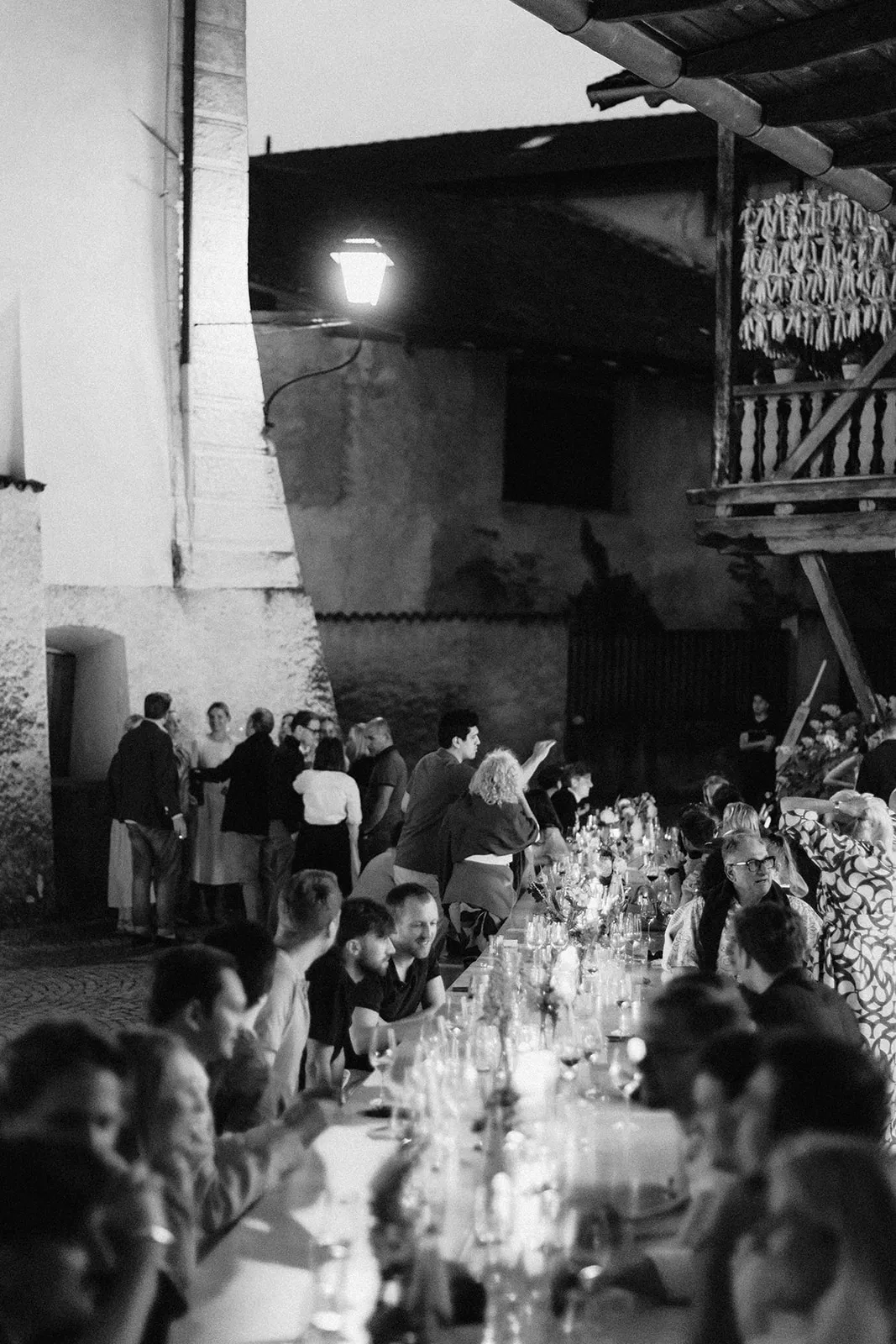 Lange Tafel bei Nacht in einem Hof in Margreid, die Gäste reden unter einer einzelnen Laterne.