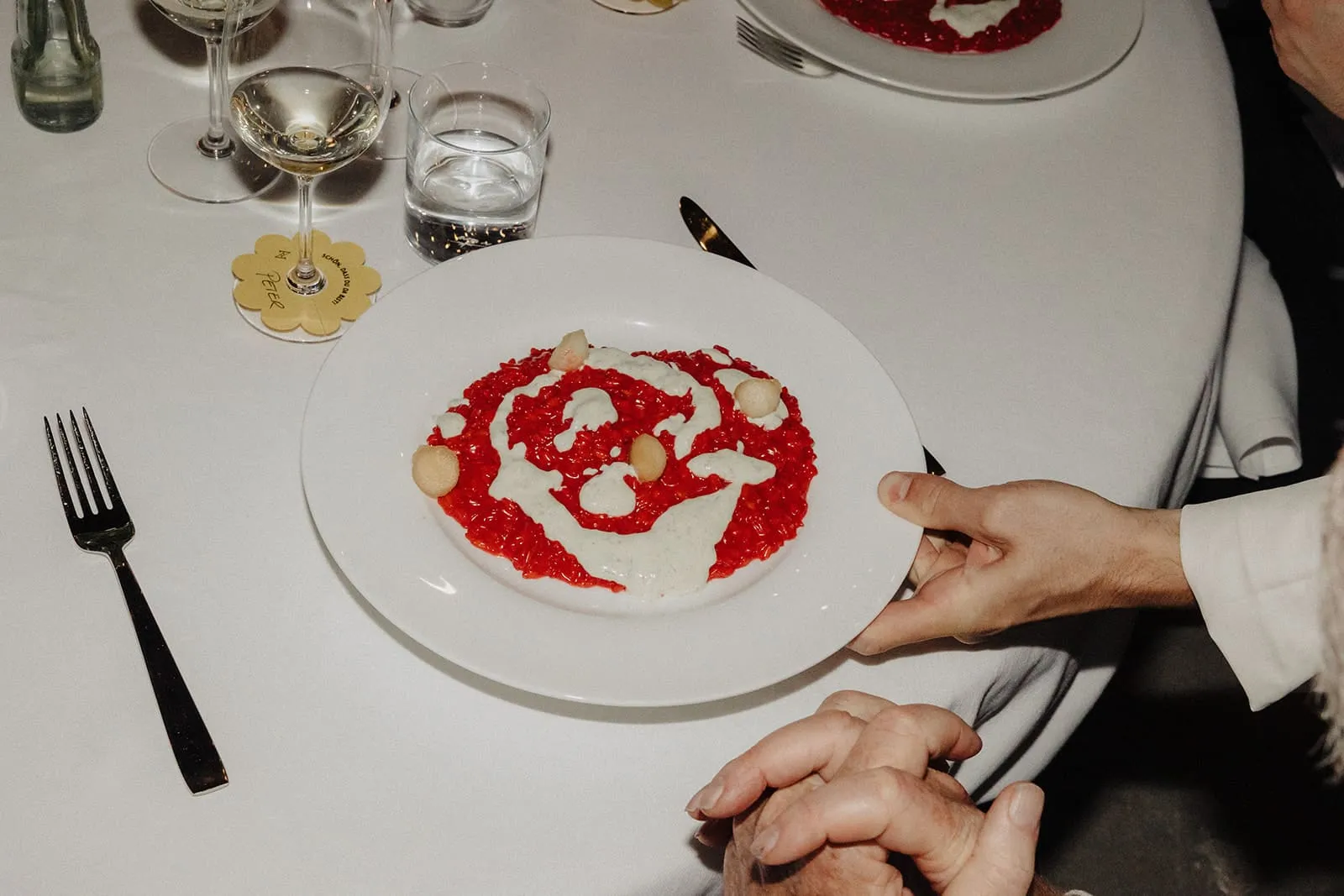 A plate of red risotto set down on the white tablecloth