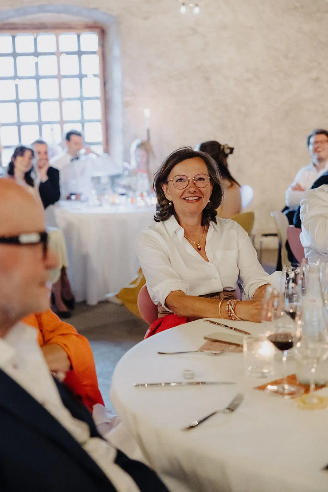 A guest laughing at the round table, the vaulted room behind her