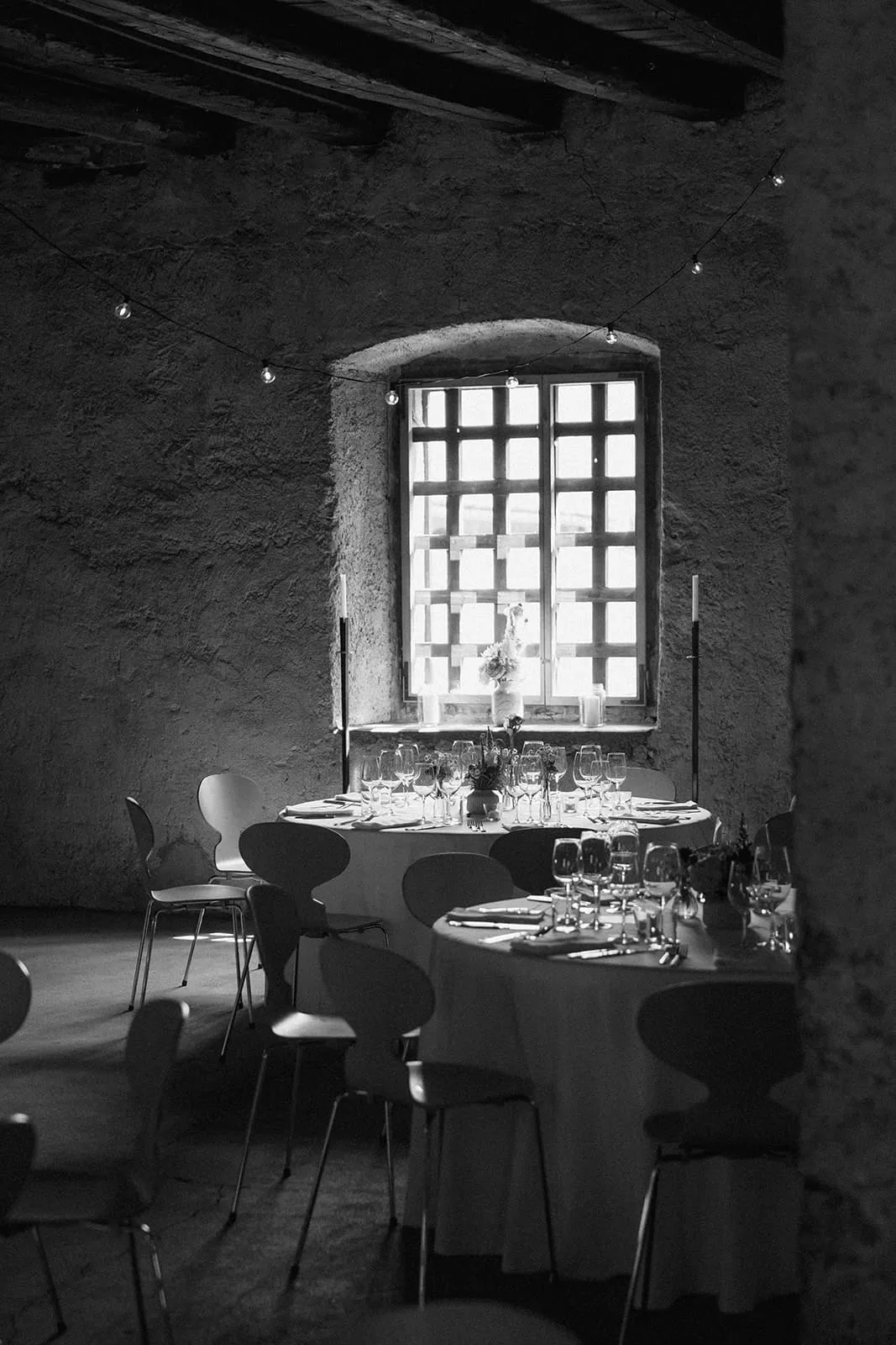 The laid tables in the vaulted room, light through the barred window