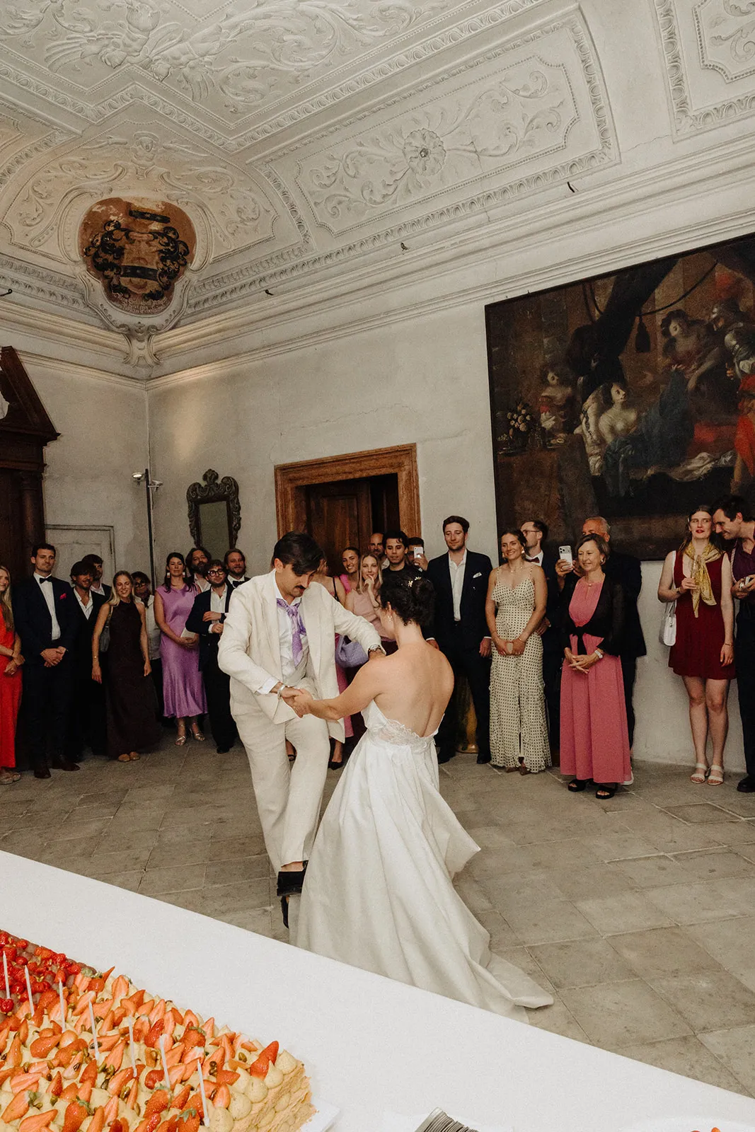 First dance in a frescoed hall, guests watching from the walls