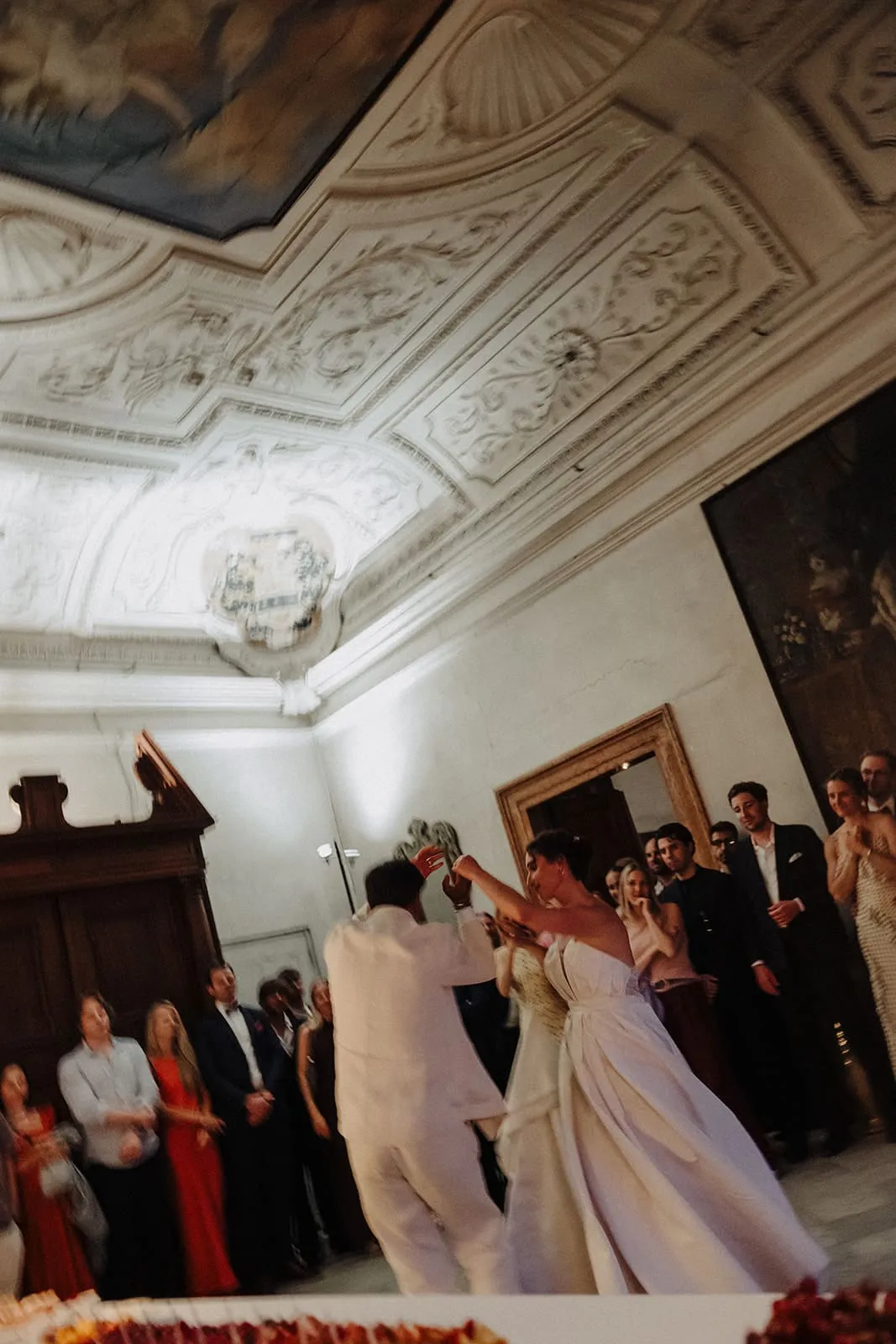 The couple dancing under the stucco ceiling, guests along the walls