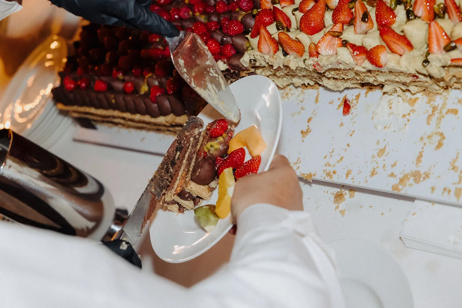 A slice being lifted from the long strawberry cake onto a plate