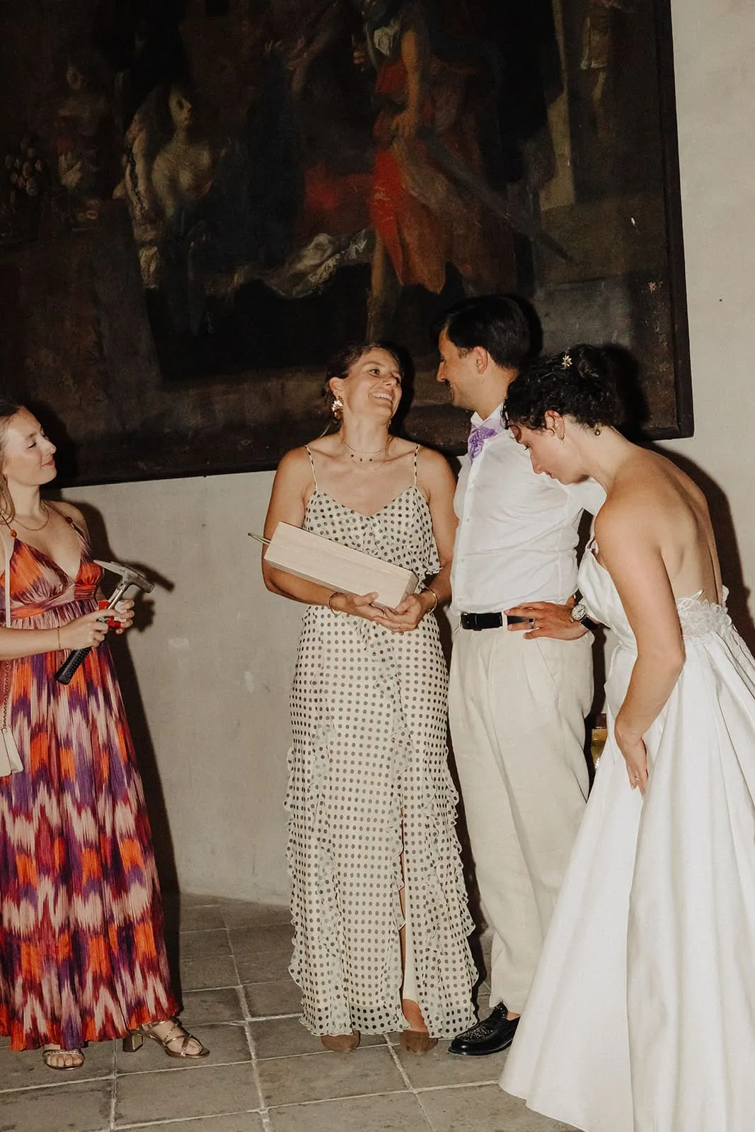 The couple talking with a guest under a painting after the cake