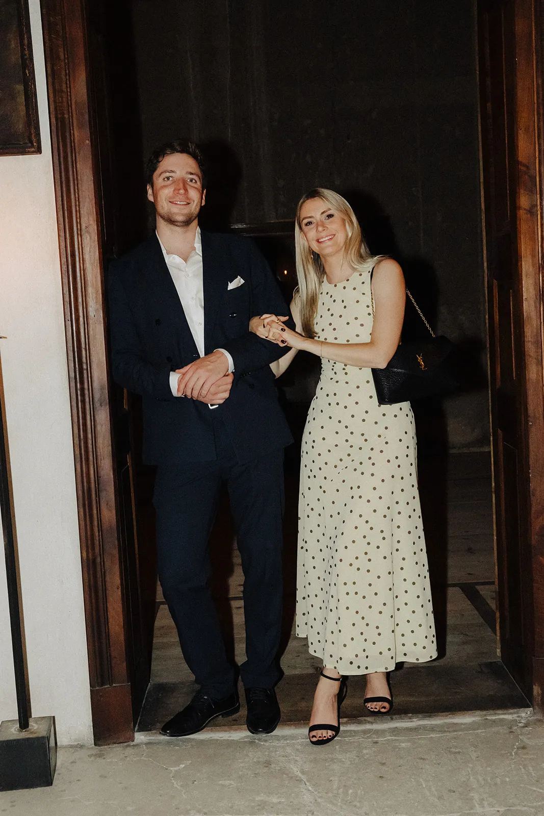 A couple standing in a bright doorway at night, laughing