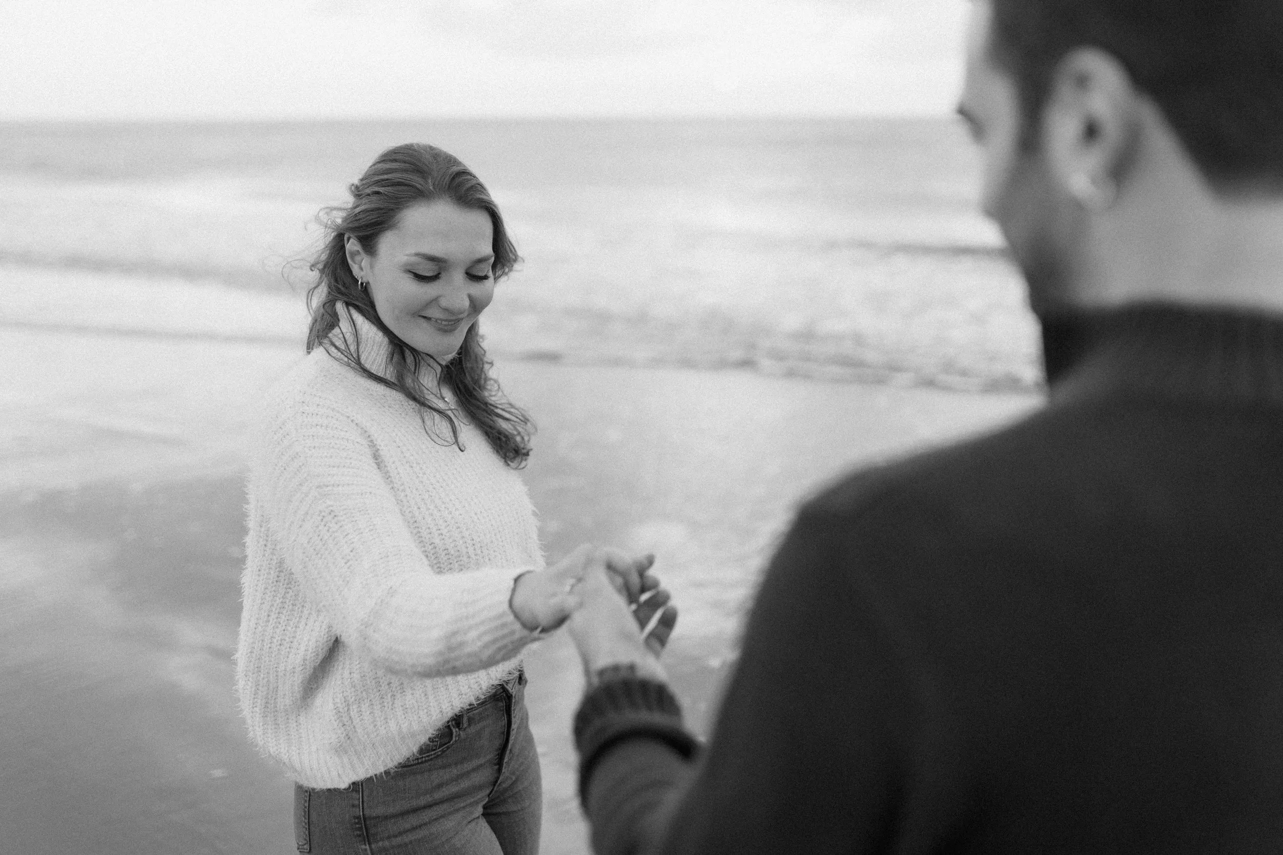 A bride laughing on the beach, the groom in the foreground