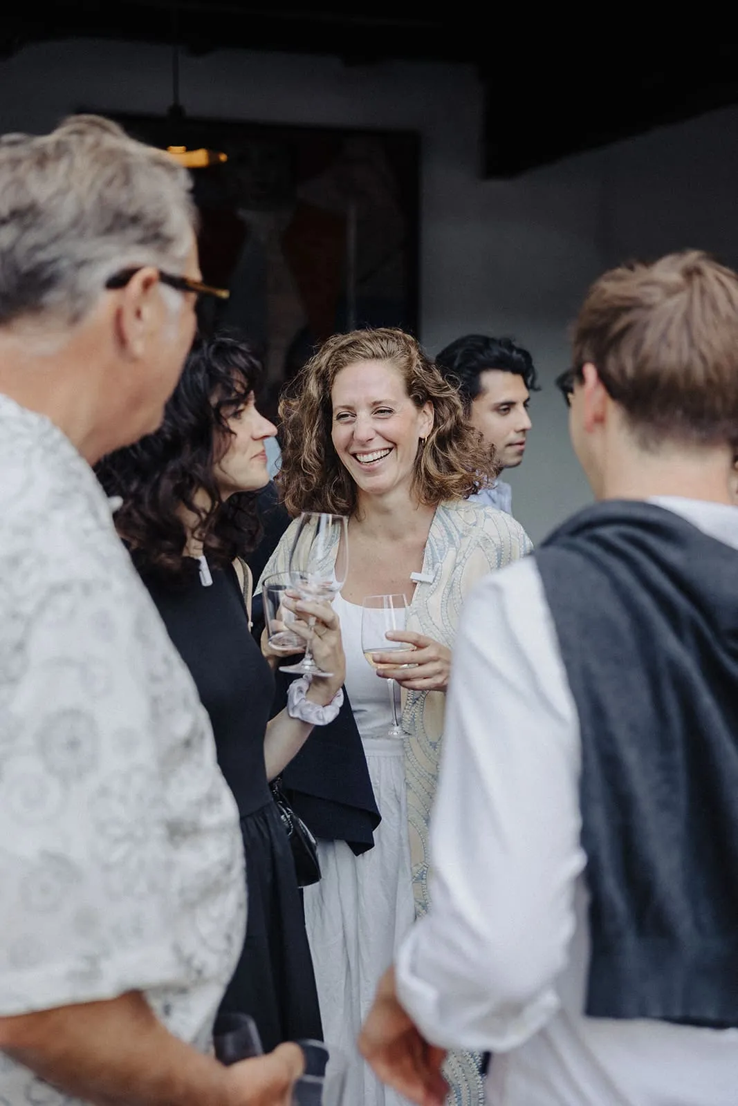 A guest laughing between the others, a glass in each hand