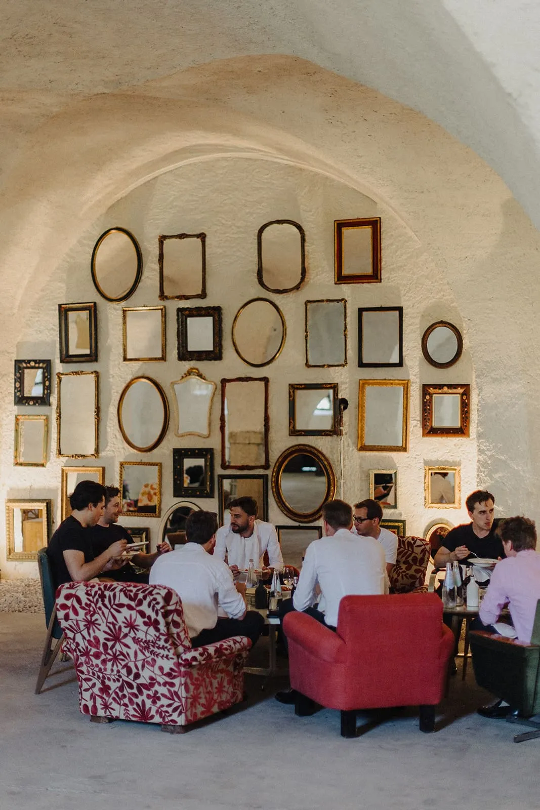 The men sitting in the vaulted room under a wall of empty frames