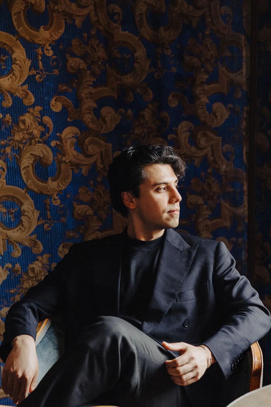 A guest sitting in front of the blue and gold wallpaper, looking out