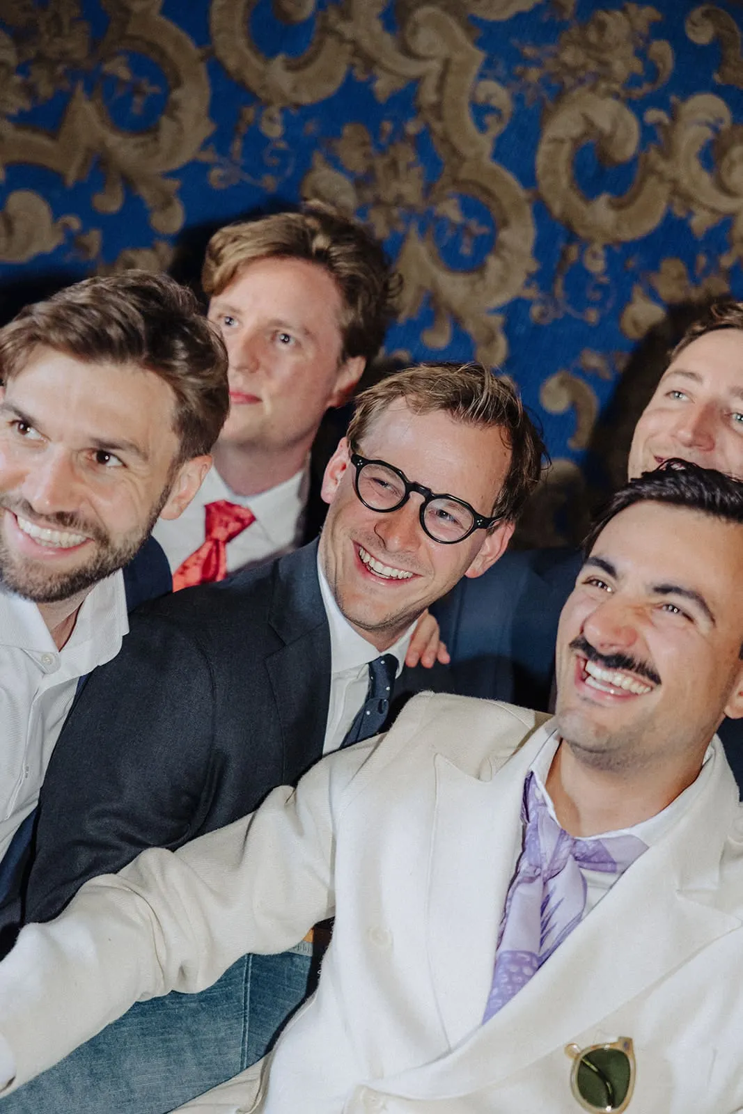 The friends pressed together in front of the blue wallpaper, laughing