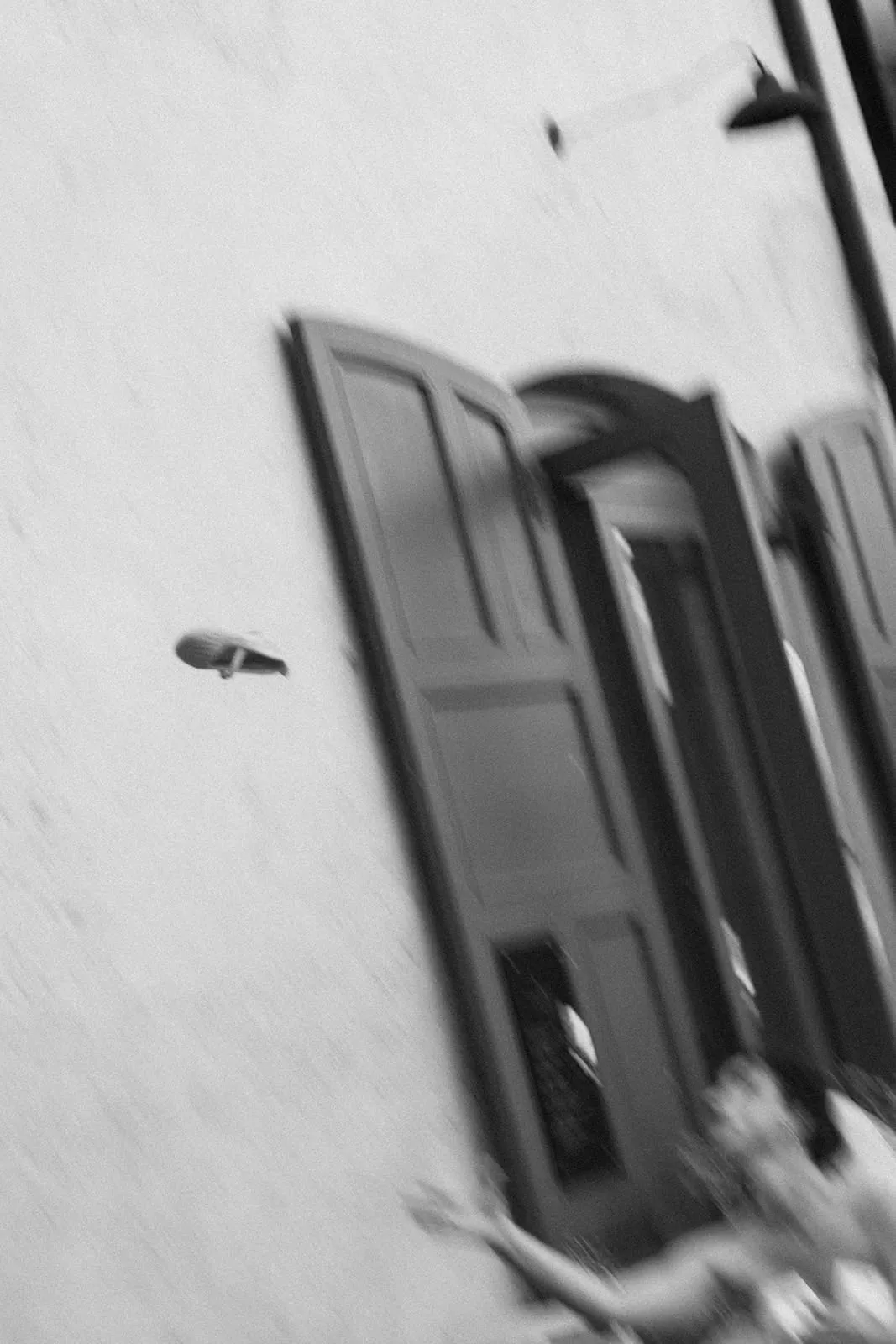 A shoe flying through the air in front of the green shutters