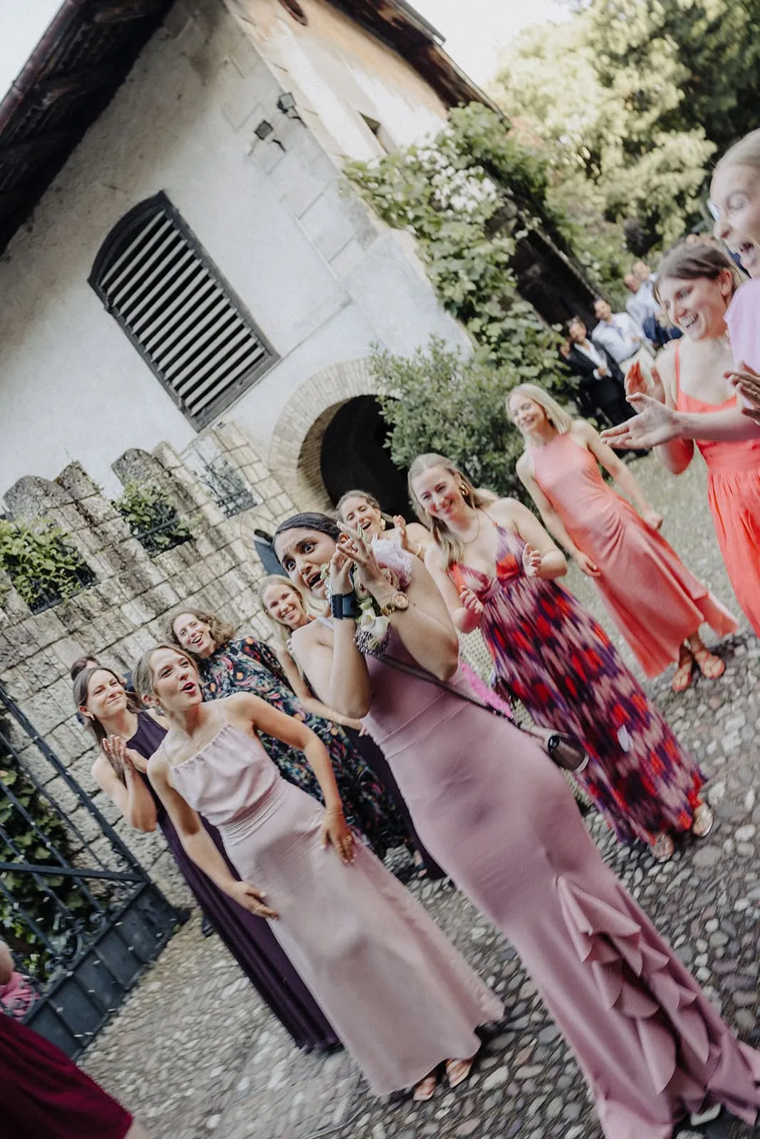 A group of guests posing and laughing in front of the old house