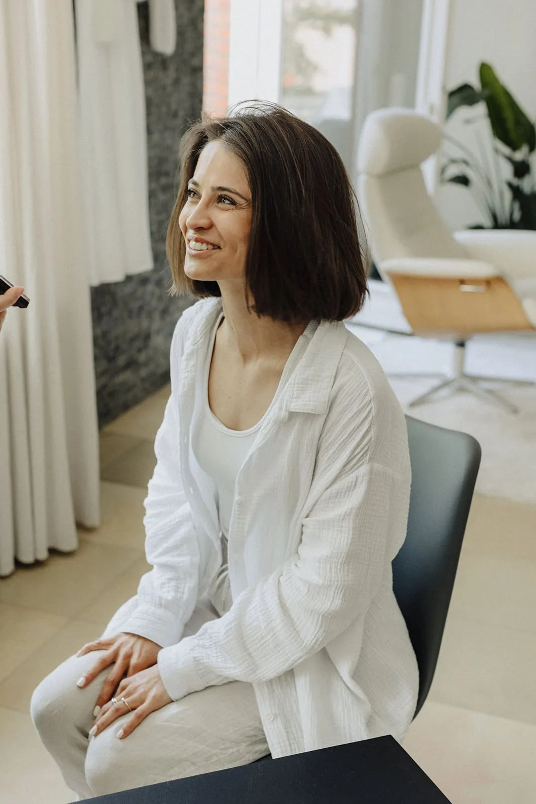 The bride sitting in her white shirt, laughing and looking up