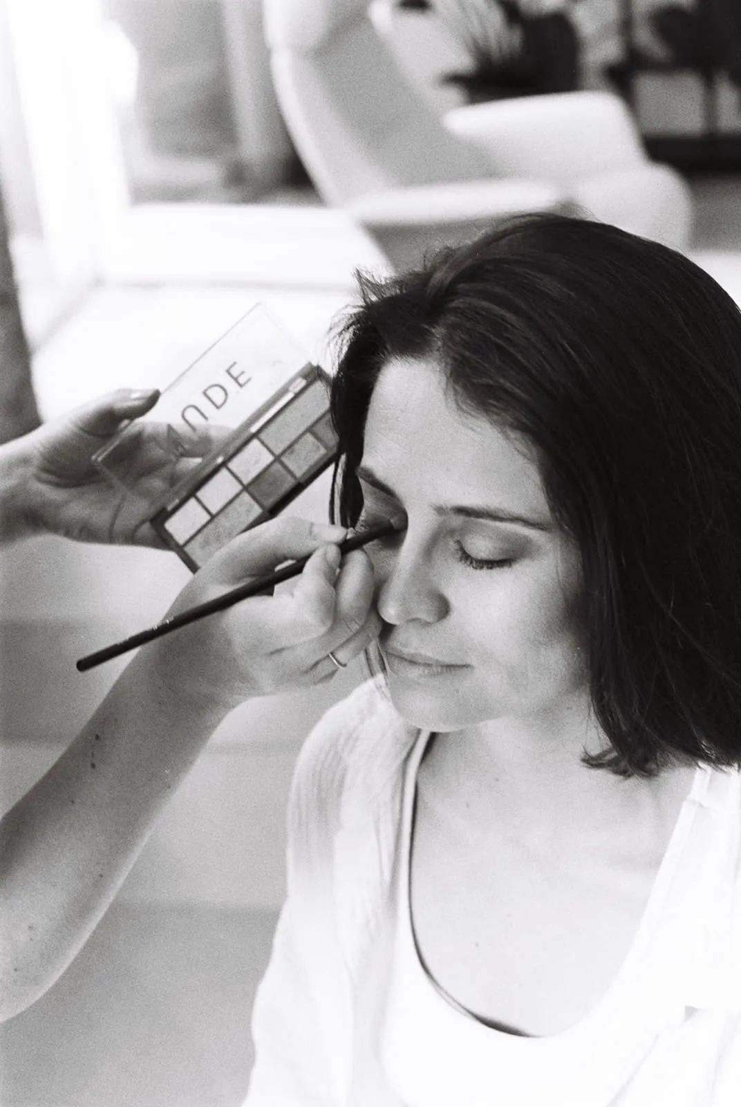 An eyeshadow palette held up beside the bride's face