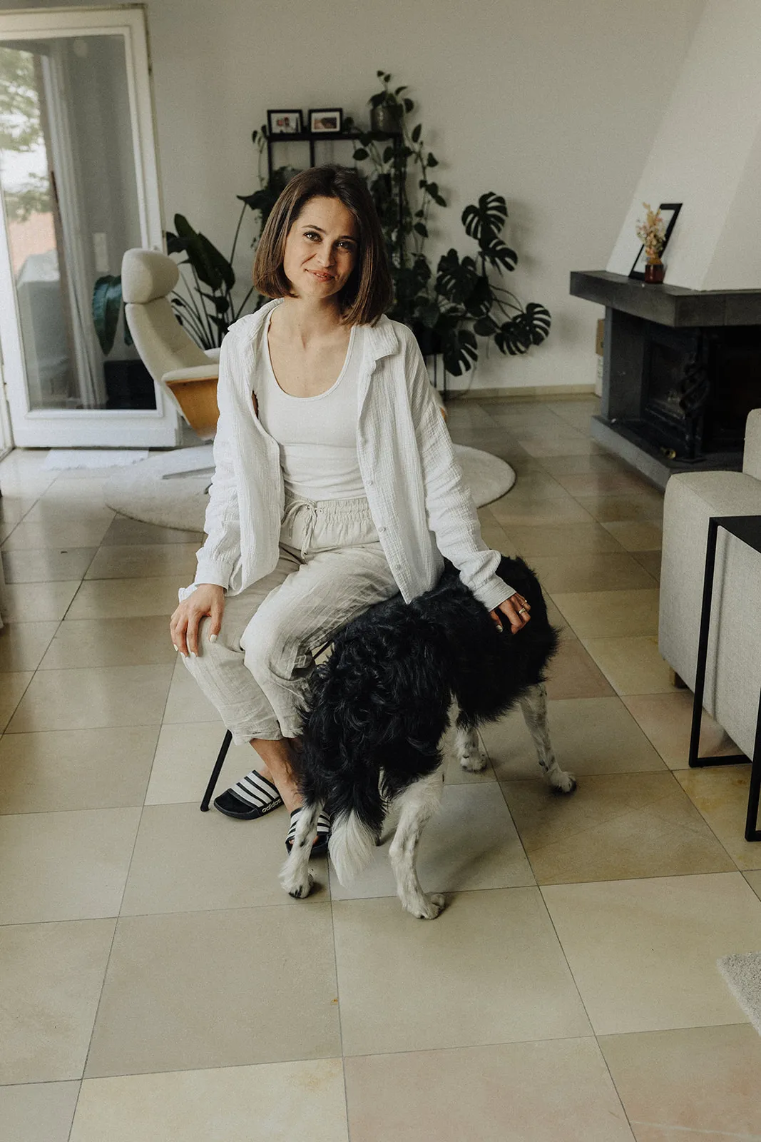 The bride crouching in a bright room with a black dog