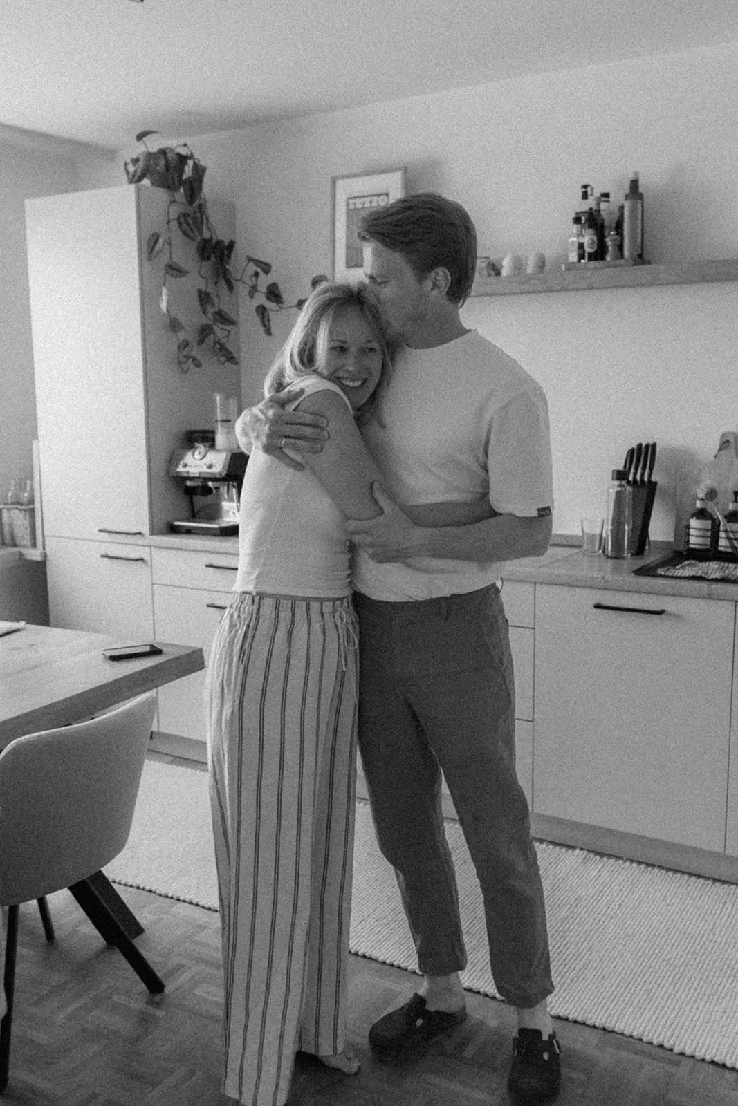 The couple holding each other in the kitchen before they dress