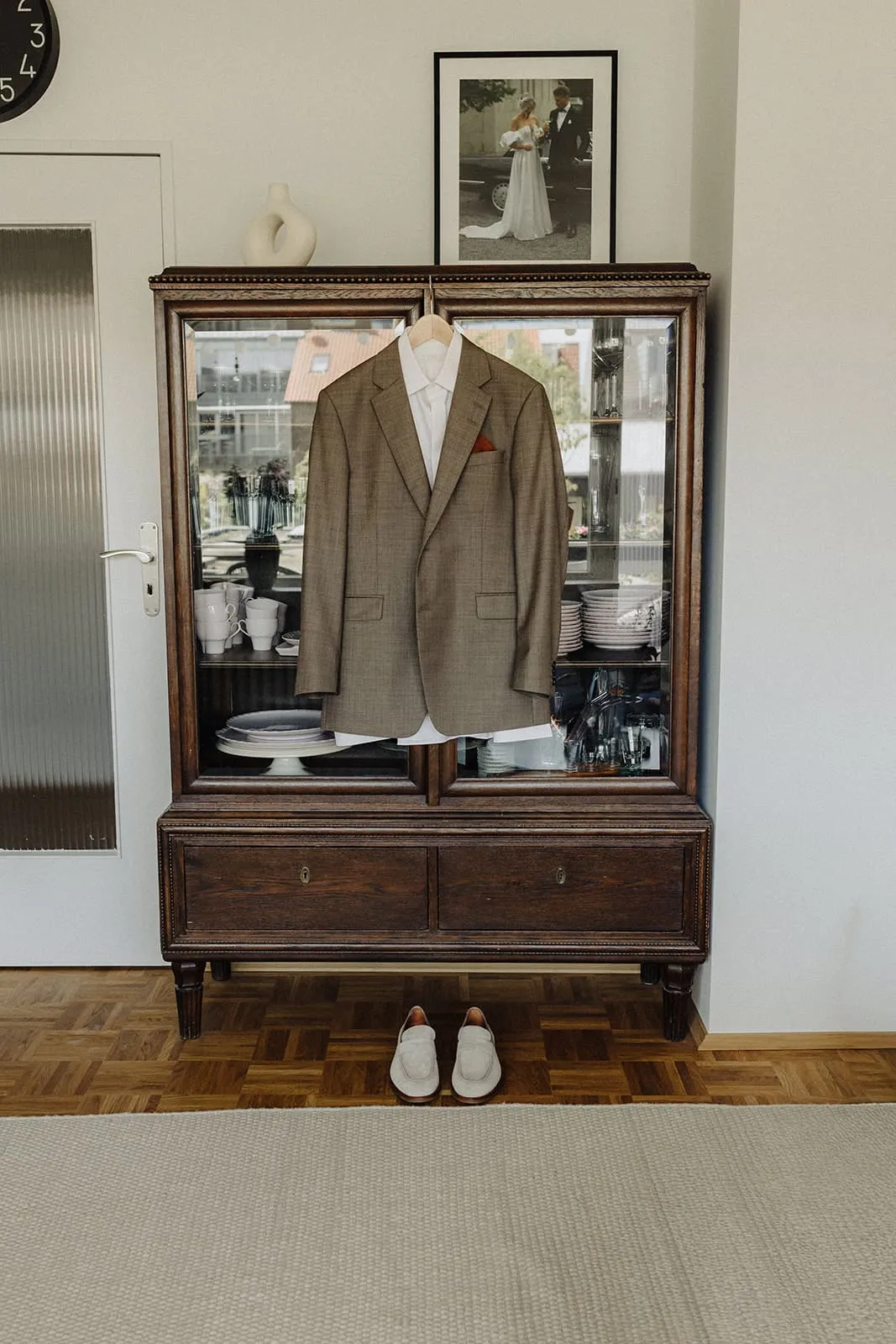The suit on the cabinet and the shoes on the parquet below it