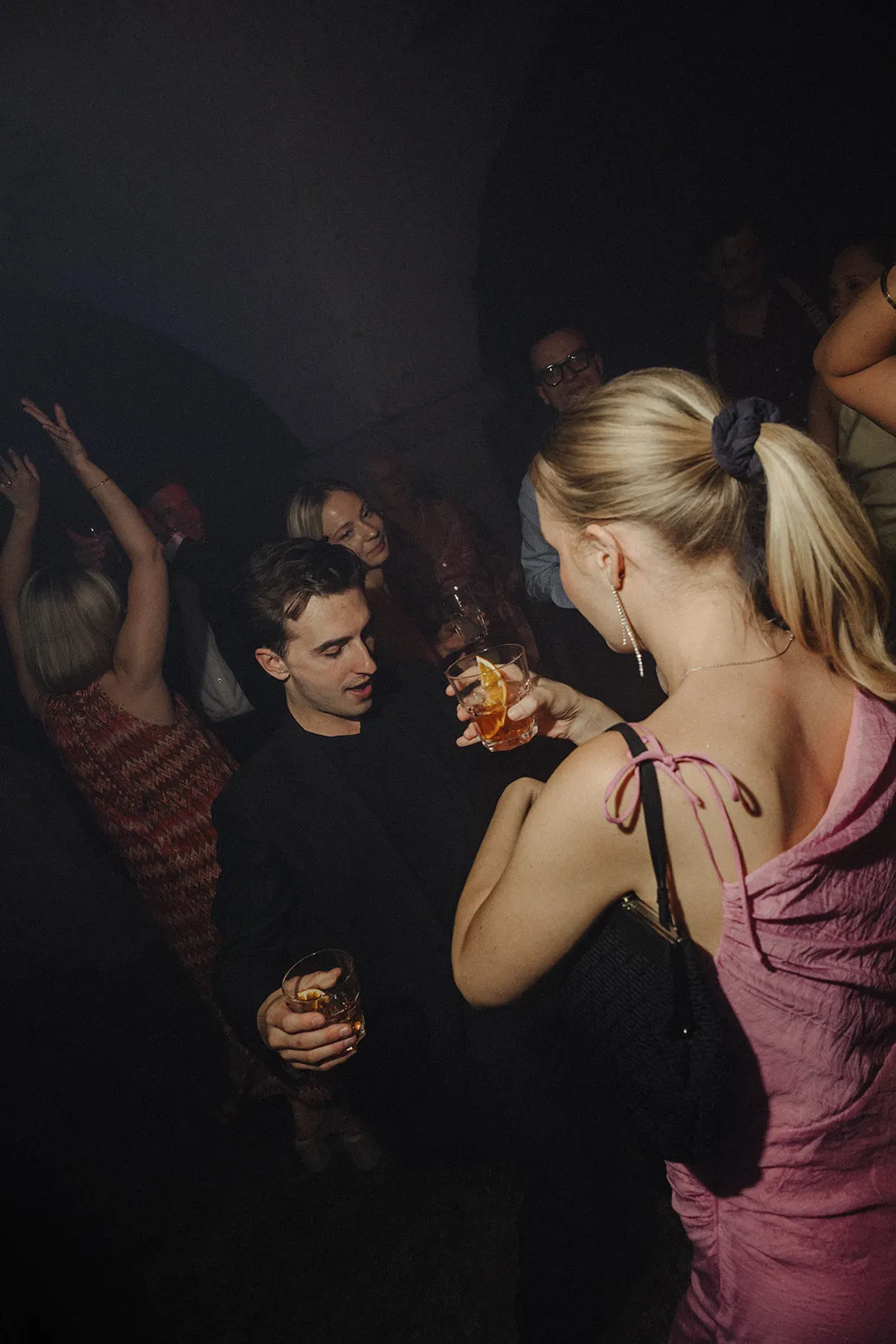 Guests dancing in the dark with drinks in their hands