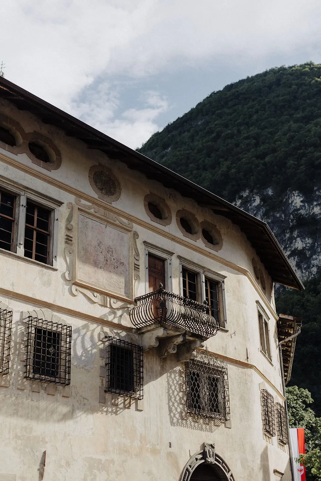 A frescoed house with a wrought iron balcony below the mountain