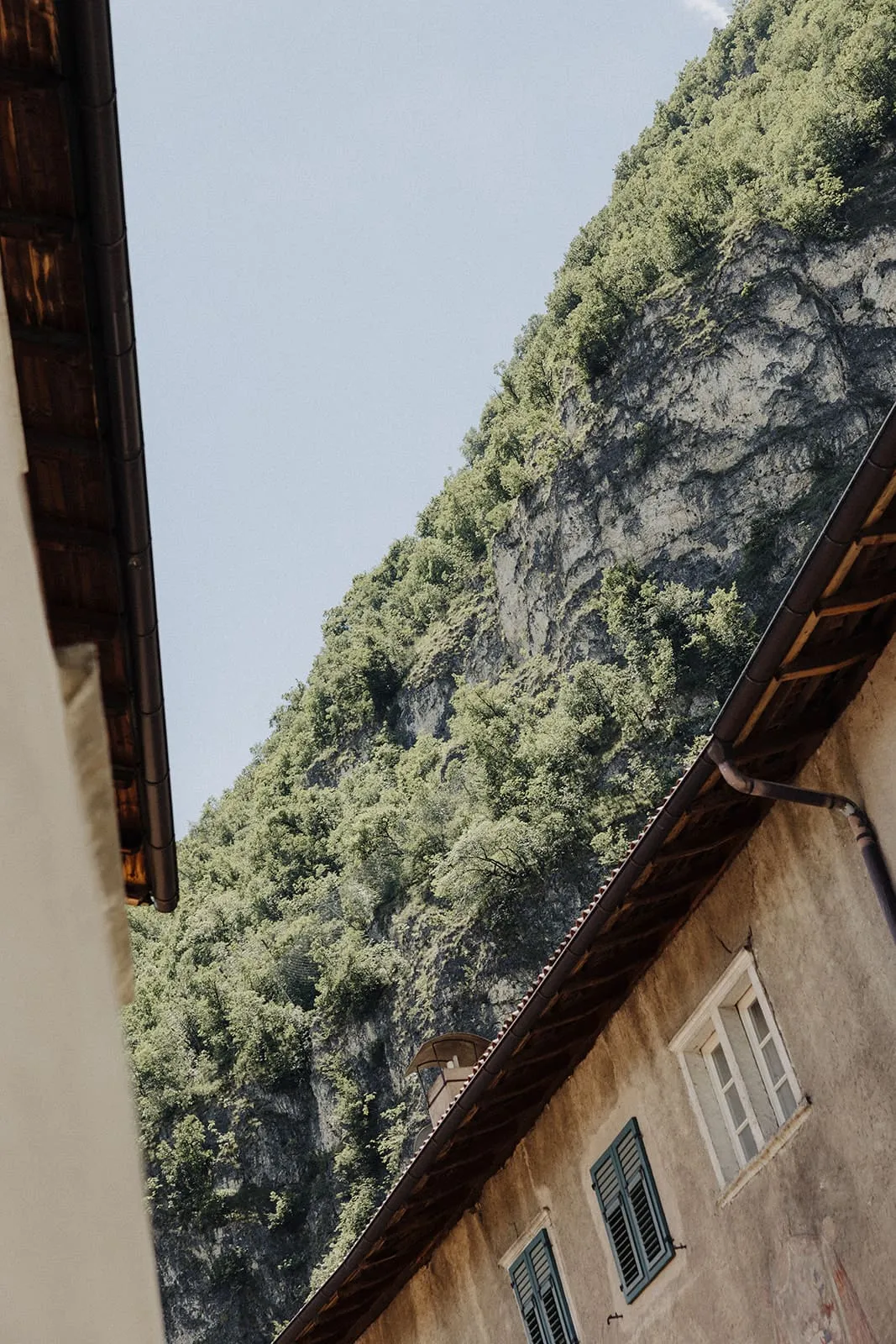 Two roofs and the wooded cliff face above the village