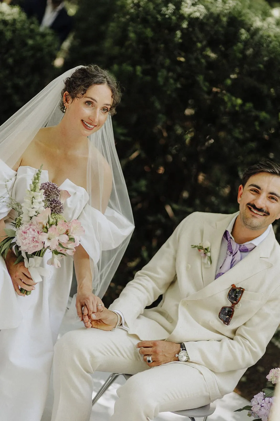 The couple sitting side by side during the ceremony, hands touching