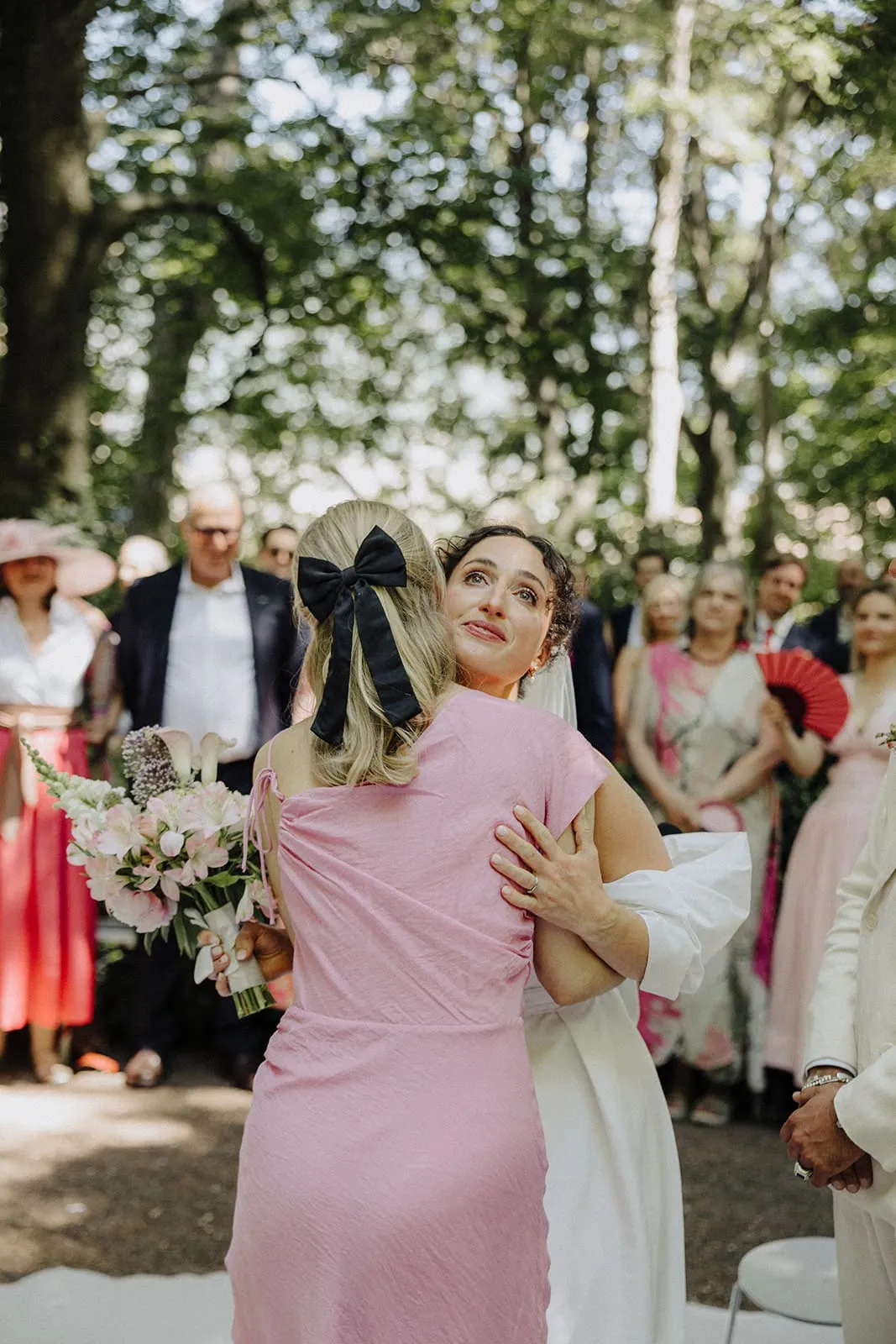 A friend in pink holding the bride at the altar, the bride looking up